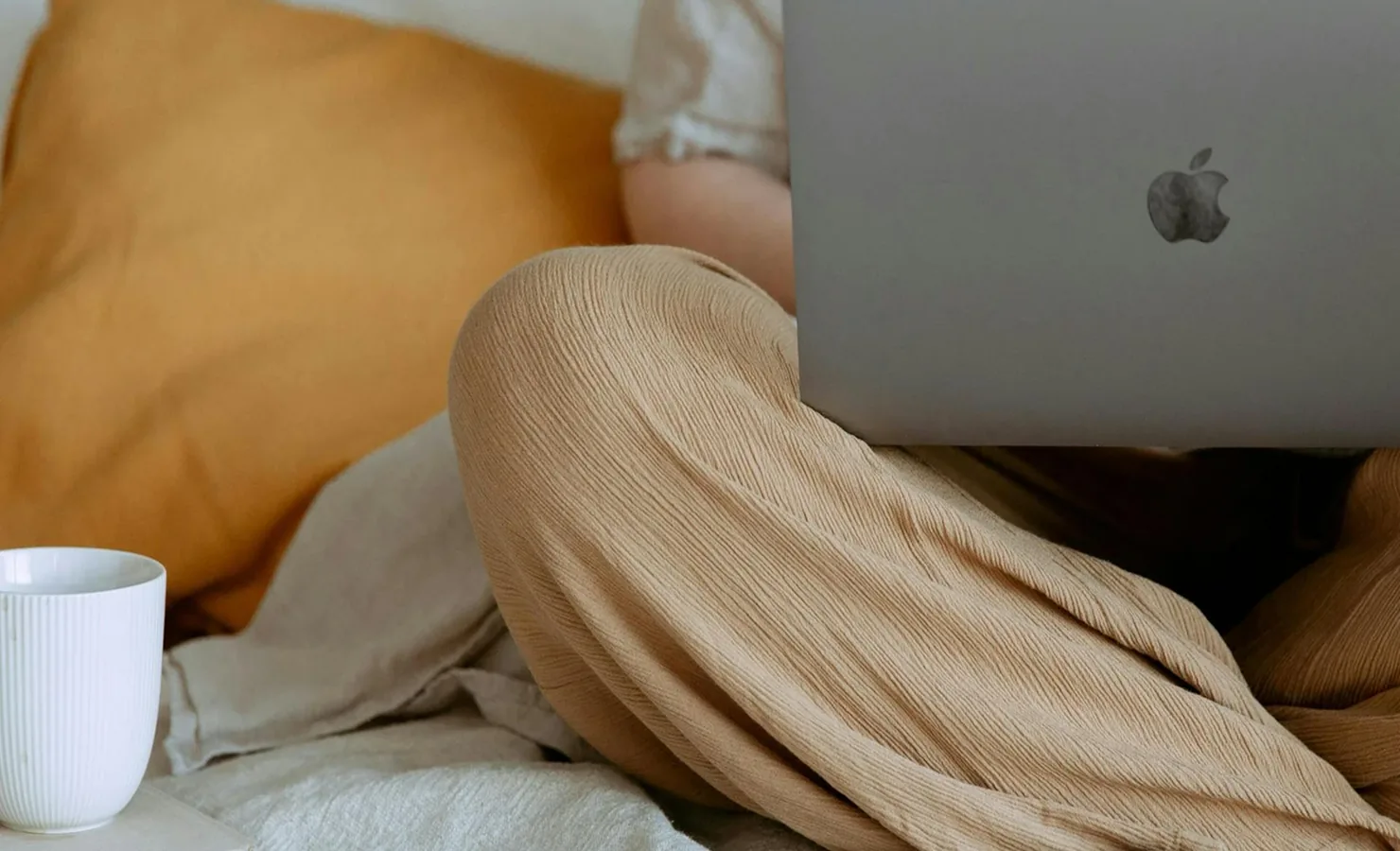 Person working on a laptop while sitting on a bed